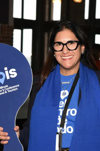 A woman in a blue scarf holding an Illinois Governor's Conference sign. 