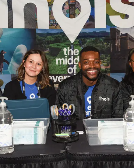 Two people smiling at an Enjoy Illinois registration table. 