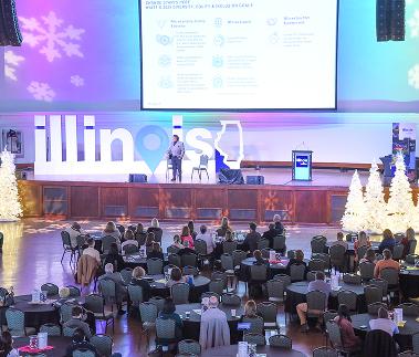 Attendees at round tables facing the main stage at the conference. 